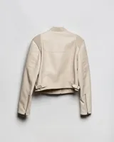Campera estilo motero de símil cuero en color beige, con cuello alto, cierre frontal asimétrico y paneles acolchados en los hombros.