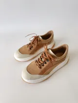 Zapatillas deportivas de cuero color camel con cordones marrones y suela blanca.