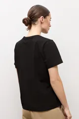 Remera blanca de manga corta con detalle de botones metálicos en el hombro, cuello redondo y corte clásico.
