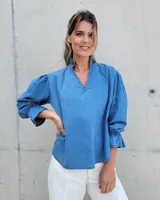 Blusa de denim azul con cuello mao y volados, mangas abullonadas con puños elásticos y escote en V.