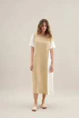 Vestido largo de lino de silueta relajada, con escote redondo, mangas cortas y bolsillos laterales. Cuenta con un diseño bicolor que combina un panel central en color tostado y los laterales y mangas en color blanco.