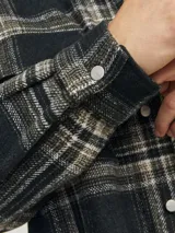 Sobrecamisa a cuadros verde oscuro, marrón y blanco, de manga larga con puños abotonados, cierre frontal con botones y bolsillos en el pecho.