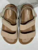 Sandalias color beige con ajuste de velcro en capellada y talón, plantilla acolchada y suela de goma antideslizante. Horma chica.