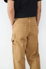 Pantalón estilo carpintero de corte holgado, color camel, con bolsillos laterales funcionales y cierre frontal de botón.