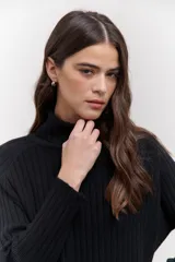 Polera de tejido de punto acanalado en color negro, con cuello alto y diseño de corte recto con largo asimétrico, más corto adelante y más largo atrás.