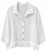 Camisa blanca de lino, con cuello camisero, cierre frontal de botones y mangas tres cuartos con detalles de pliegues en los puños y el ruedo.