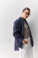 Camisa celeste de corte oversize, con mangas largas, cuello camisero y cierre frontal de botones.