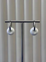 Aros tipo argolla con dije en forma de dona de vidrio color blanco. Base de plata 925.