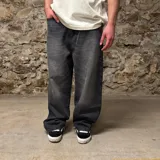 Jean de corte super baggy en color gris oscuro con efecto lavado. Presenta un diseño de pierna ancha y holgada, con bolsillos traseros amplios que incluyen bordados gráficos con texto.