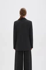 Blazer de corte holgado con diseño de rayas verticales, cuello solapa y cierre frontal con un botón. Presenta bolsillos laterales con solapa y mangas largas.