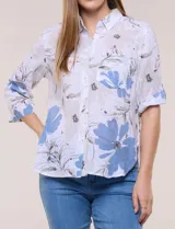 Camisa de lino sintético con estampado floral en tonos azules y beige sobre fondo blanco, de corte holgado, mangas tres cuartos y cuello camisero.