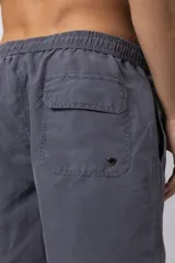 Short de baño color marrón rojizo, con cintura elastizada y cordón de ajuste. Presenta un pequeño parche con logo en la parte inferior izquierda.