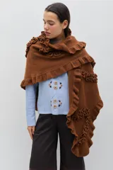 Chal de lana color marrón con diseño envolvente, decorado con volados aplicados en toda la superficie que aportan textura y movimiento.