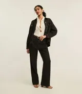 Pantalón wide leg negro de sarga de algodón, con cintura alta, trabillas, bolsillos delanteros y traseros, y cierre con botón y cremallera.