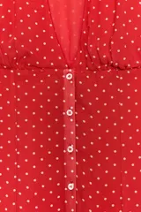 Vestido corto rojo con estampado de lunares blancos, cuello redondo con escote en pico pronunciado, manga muy corta y cierre frontal con botones.
