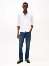 Camisa blanca de algodón con tecnología Flex, corte slim fit, cuello abotonado, mangas largas con puños redondeados y logo de Tommy Hilfiger bordado en el pecho.