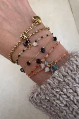 Pulsera de cadena dorada con dijes de piedras naturales y cuentas de colores. Presenta un diseño delicado con eslabones finos y cierre de mosquetón.
