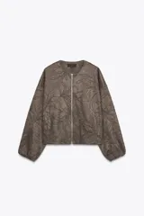 Chaqueta bomber color marrón con cuello redondo, manga larga con puño elástico y cierre frontal de cremallera metálica. Presenta un diseño de bordados florales en relieve por toda la prenda y bolsillos delanteros de vivo.