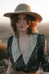 Vestido midi con estampado floral en tonos marrones y azules, cuello en V con detalle de puntilla blanca, mangas cortas abullonadas y cinturón marrón con hebilla dorada.