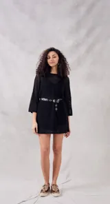 Minivestido negro de calados con mangas 3/4 y cinturón con hebilla metálica.