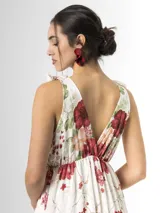 Vestido largo confeccionado en mezcla de tencel y lino, con fondo off white y estampado floral en tonos rosados, rojos y verdes. Cuenta con escote en V pronunciado, breteles anchos ajustables con lazos en los hombros, corte bajo el busto y falda amplia con volados escalonados.