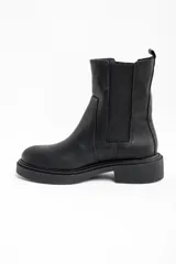 Bota tipo Chelsea de cuero negro, con paneles elásticos laterales y suela de goma con plataforma baja.