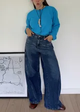 Jean wide leg de tiro medio, color azul, con cortes diagonales y estampa de flor en los bolsillos traseros.