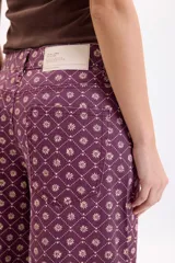 Jean ancho de tiro medio/alto en color bordó con estampa geométrica y floral en tono crudo, de corte holgado estilo palazzo y bolsillos traseros.