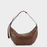Cartera tipo hobo de diseño curvo en color marrón, con acabado brillante y correa ajustable integrada. Presenta cierre superior y logo metálico en la parte inferior frontal.