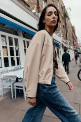 Campera bomber color beige, de cuello redondo y manga larga. Tiene bolsillos delanteros y bajo acabado en elástico. Cierre frontal con cremallera.