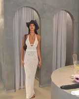 Vestido largo de tejido de punto calado color crema, con escote halter y espalda descubierta.