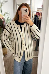 Saco tejido de punto con diseño a rayas verticales, cuello redondo y cierre frontal con botones. Presenta puños con detalle de volados en color azul oscuro.