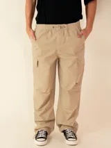Pantalon cargo de corte holgado, color beige, confeccionado en sarga de algodón. Presenta cintura elástica con cordón de ajuste, bolsillos laterales tipo cargo y diseño de pierna recta.