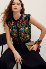 Chaleco corto negro cubierto de lentejuelas brillantes con un patrón floral multicolor en tonos verdes, rojos, azules y dorados.