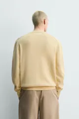 Sweater de punto en mezcla de algodón, color beige, con cuello en V y mangas largas. Presenta terminaciones en rib en cuello, puños y ruedo.