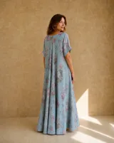Vestido largo celeste con estampado floral rosado y gris, escote en V y mangas cortas con vuelta.