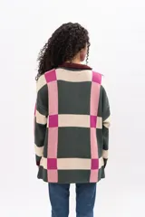 Saco largo de punto con diseño geométrico de cuadros en tonos verde, rosa y crema. Presenta cuello tipo polo, cierre frontal con botones y puños en color bordó.