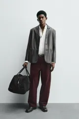 Pantalón de hombre color bordó oscuro, de corte ancho (wide fit), confeccionado en tejido de algodón con acabado flocada o efecto aterciopelado. Presenta cinco bolsillos y cierre frontal con cremallera y botón.