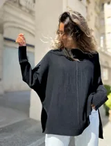 Sweater de punto color negro, con diseño oversize, cuello redondo, costura central vertical y aberturas laterales en el ruedo. Presenta mangas largas con puños acanalados.