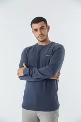 Sweater de punto color ladrillo, con cuello redondo y logo bordado en el pecho.