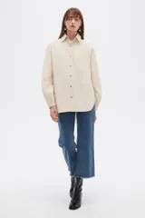Campera camisera de algodón color beige, de manga larga con puños elásticos, cuello camisero, cierre frontal con botones a presión y un bolsillo aplicado en el pecho.