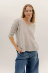 Buzo de lambswool color beige, con escote en V, mangas 3/4 y corte holgado con tajos laterales.