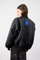 Campera bomber negra con cuello, puños y cintura acanalados. Presenta cierre frontal y bolsillos laterales. En la espalda tiene bordada la palabra "Bestia" en letras góticas blancas.