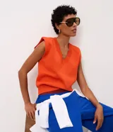 Chaleco de tricot naranja con escote en V profundo, hombreras internas y terminaciones acanaladas en cuello, sisas y bajo.