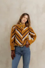 Sweater de punto jacquard con diseño de chevron en tonos mostaza, marrón y crema. Presenta cuello redondo, corte holgado y mangas largas abullonadas en los hombros con detalle de trenzado lateral.