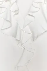 Camisa sin mangas color rosa pálido, con escote en V y volantes que recorren el borde del escote y el centro del delantero.