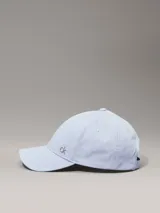 Gorra de béisbol de algodón en color celeste pálido, con visera curva y un pequeño herraje metálico con el logo 'ck' en la parte delantera.