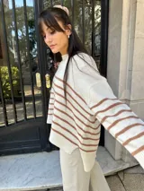 Sweater tejido color crema con rayas horizontales marrones, cuello redondo y corte holgado.
