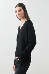 Sweater verde de tejido de punto, con escote en V y mangas largas.
