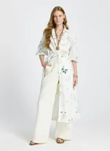 Vestido camisero midi blanco con estampado floral, cuello camisero, mangas 3/4 abullonadas, cierre frontal con botones y lazo ajustable en la cintura.